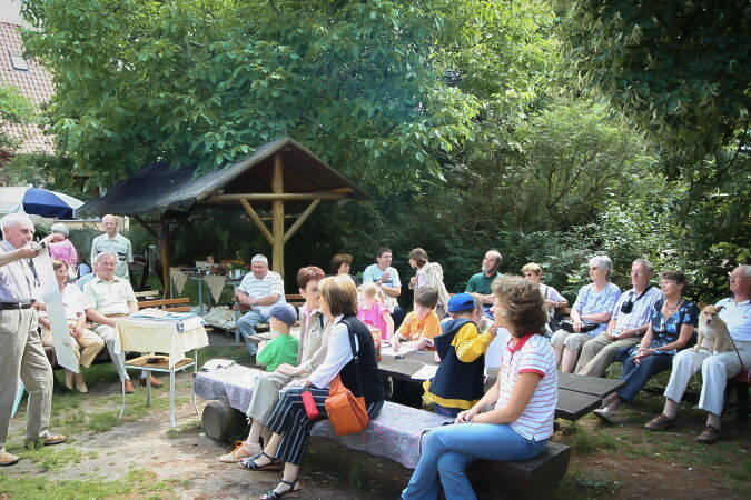 Dr. Chr.Kaatz hält einen Vortrag die Holzbänke mit den Besuchern stehen unter freiem Himmel